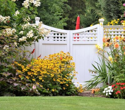 colorful flower garden against a white fence