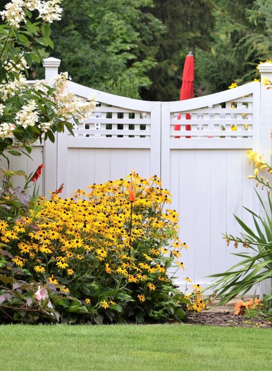 colorful flower garden against a white fence